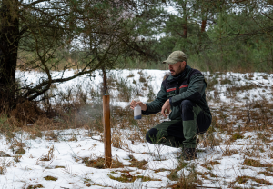 Ein Mitarbeiter der Naturwacht besprüht einen Lockstock mit Baldrian-Tinktur.